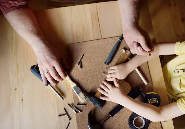 Hombre maduro y niño hacen un juguete de madera juntos.
