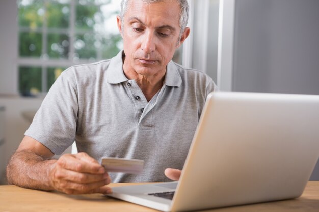 Hombre maduro pensativo usando su computadora portátil