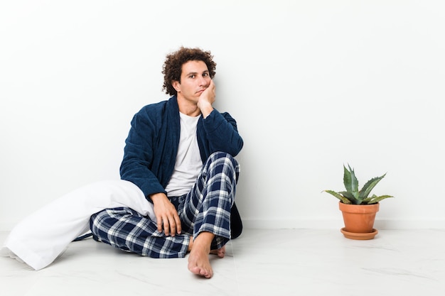 Foto hombre maduro con pijama sentado en el piso de la casa que está aburrido, cansado y necesita un día de relax.