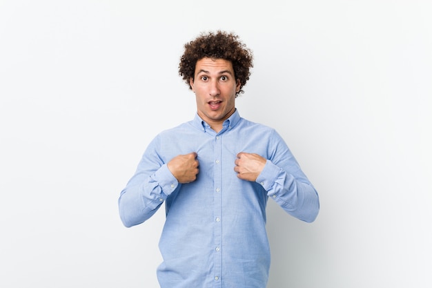 El hombre maduro rizado joven que llevaba una camisa elegante sorprendió señalar con el dedo, sonriendo ampliamente.