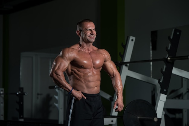 Hombre maduro sano de pie fuerte en el gimnasio y flexionando los músculos Muscular culturista atlético Fitness masculino posando después de los ejercicios