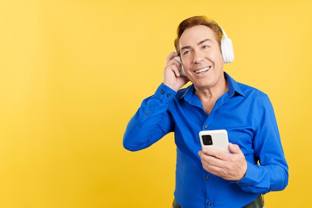 Hombre maduro sonriente escuchando música con el móvil