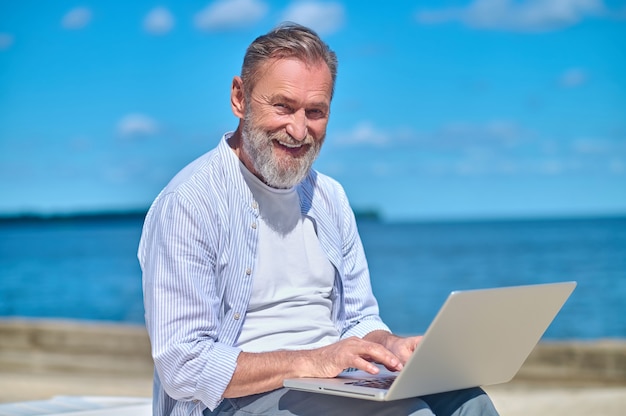 Hombre maduro sonriente con laptop en la naturaleza