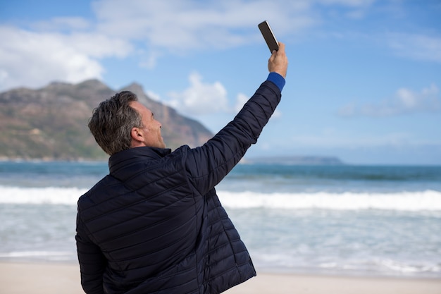 Hombre maduro tomando una selfie desde un teléfono móvil en la playa