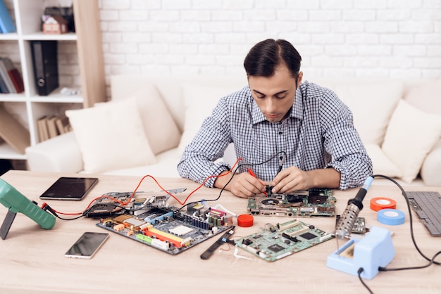 Hombre maestro reparando electrodomésticos en la mesa en casa.