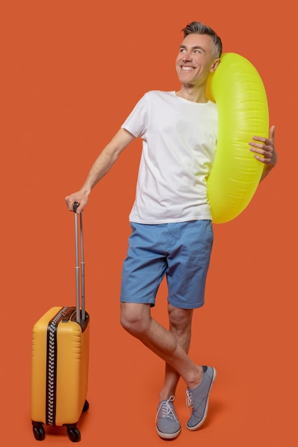 Foto hombre con maleta y anillo inflable