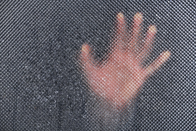 Hombre mano detrás de vidrio mojado closeup