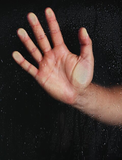 Foto hombre mano detrás de vidrio mojado closeup