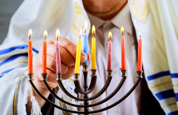 Hombre mano encendiendo velas en menorá sobre la mesa Hanukkah