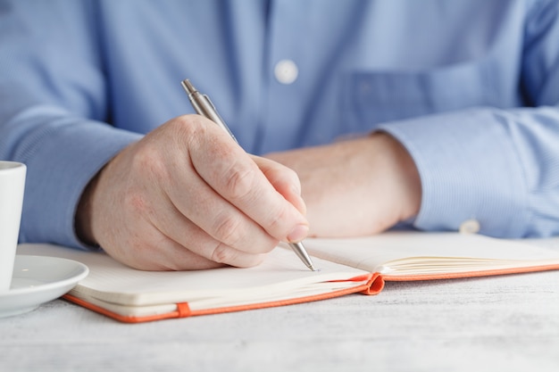 Hombre mano escribiendo en cuaderno con pluma