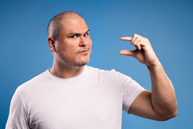 Foto hombre con la mano izquierda levantada a nivel del rostro sugiriendo algo pequeño