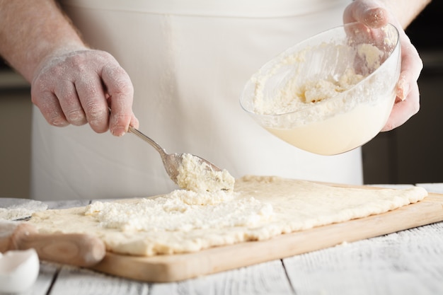 Hombre mano recogiendo queso fundido del recipiente de vidrio para tarta de queso