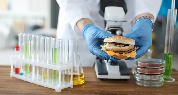 Hombre mano sostenga hamburguesa en mano con guantes protectores azules