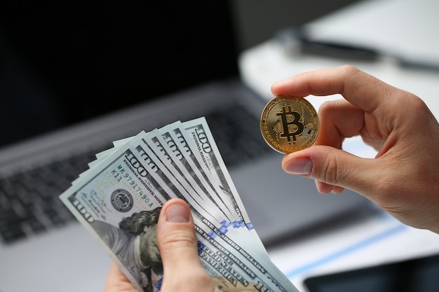 Hombre mano sostiene bitcoin y moneda de un dólar