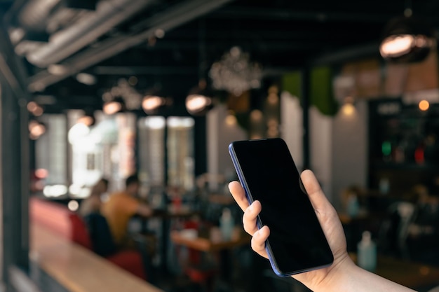 hombre de mano teléfono inteligente en el fondo de la cafetería