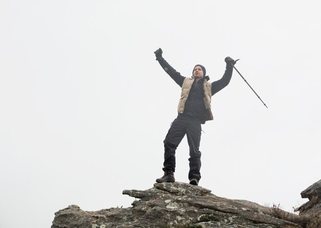 Foto hombre con manos levantadas en la roca contra el cielo