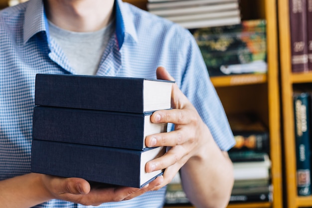 Hombre manos sosteniendo una pila de libros.