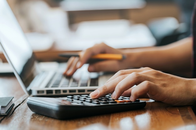 Hombre manos usando una calculadora y una computadora portátil para calcular con papel financiero