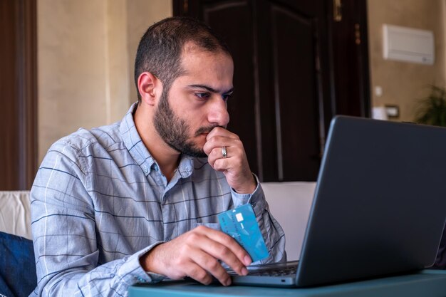 Hombre con las manos usando teléfono inteligente y computadora portátil para comprar en línea en casa