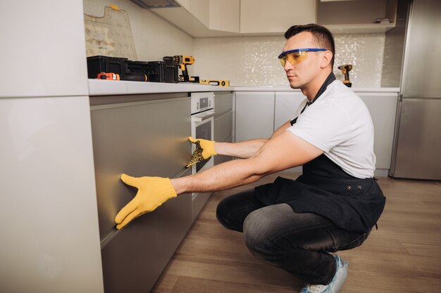 Hombre de mantenimiento instalando muebles de cocina