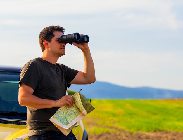 Hombre con mapa y binoculares en el campo