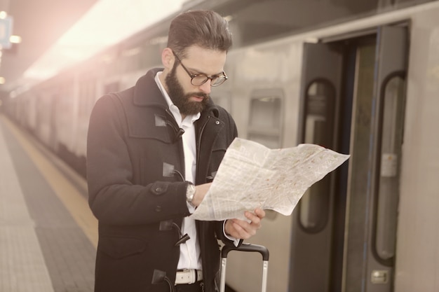 Hombre con un mapa en la plataforma del ferrocarril