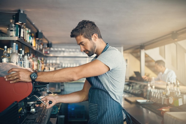 El hombre en la máquina de café y el barista preparan el pedido de bebidas con cafeína con el proceso y la producción en la industria hotelera