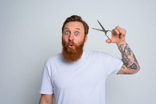 El hombre maravillado con tijeras está listo para cortar la barba.