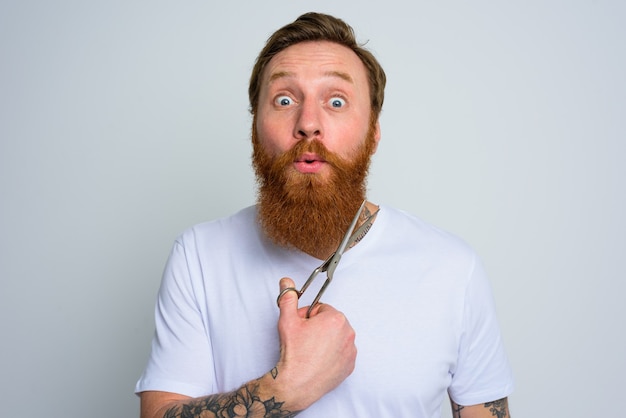 El hombre maravillado con tijeras está listo para cortar la barba.