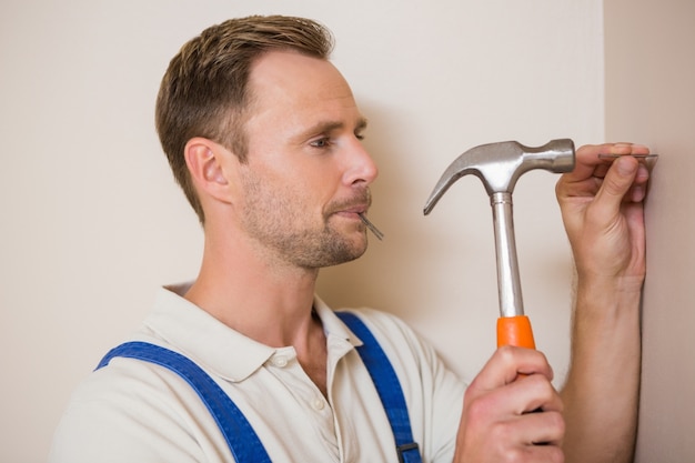 Hombre martillando clavos en la pared