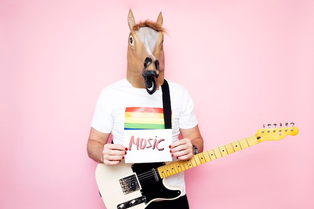 hombre con máscara de caballo sostiene un cartel que pone música