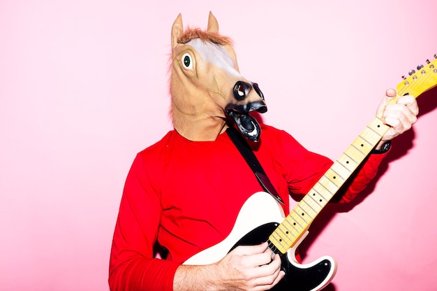 Hombre con máscara de caballo tocando la guitarra eléctrica