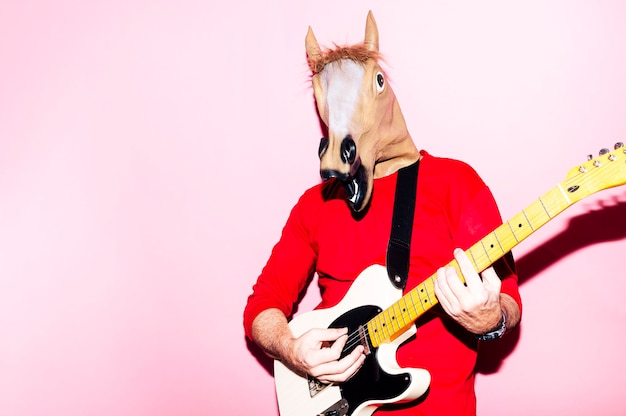 Hombre con máscara de caballo tocando la guitarra eléctrica