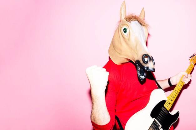 Hombre con máscara de caballo tocando la guitarra eléctrica