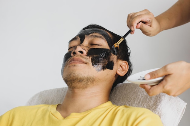 Hombre con máscara cosmética en el salón de spa