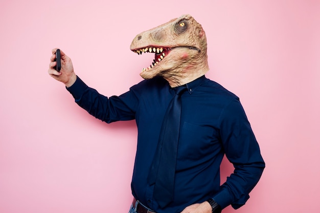 Hombre con máscara de dinosaurio tomando un selfie con smartphone | Foto  Premium