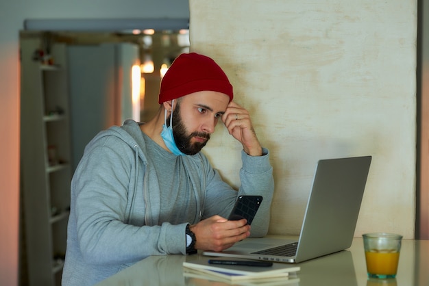 Un hombre con una máscara facial trabajando en su computadora portátil