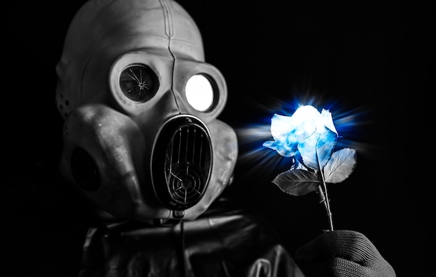 Hombre de la máscara de gas con flor azul luminosa. Influencia de la radiación. Contaminación ambiental. Concepto de Chernobyl. Energía nuclear peligrosa. Desastre ecológico.