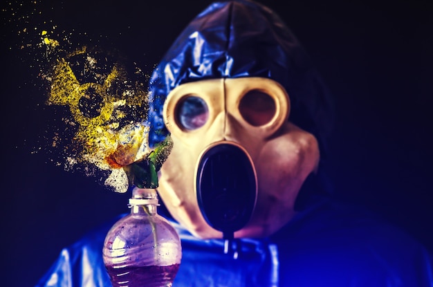 Hombre de la máscara de gas sosteniendo una botella de plástico con flores cayendo en pedazos. Influencia de la radiación. Contaminación ambiental. Concepto de Chernobyl. Energía nuclear peligrosa. Desastre ecológico.