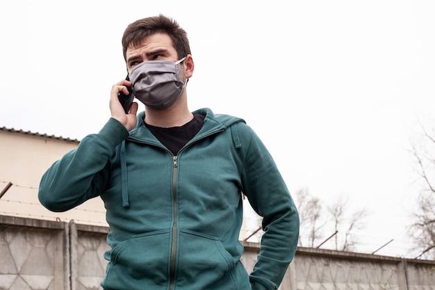 Foto un hombre con una máscara médica gris al aire libre.