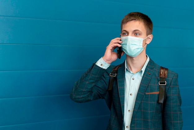 Foto hombre con máscara médica y mochila hablando por teléfono