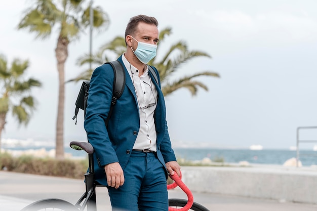 Hombre con máscara médica de pie junto a su bicicleta