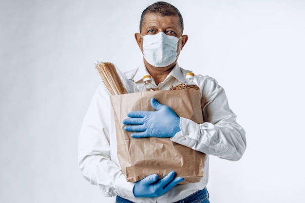 Hombre con una máscara médica protectora con una bolsa de una tienda de comestibles. Entrega de comida