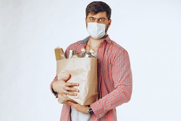 Hombre en una máscara médica protectora con una bolsa de una tienda de comestibles