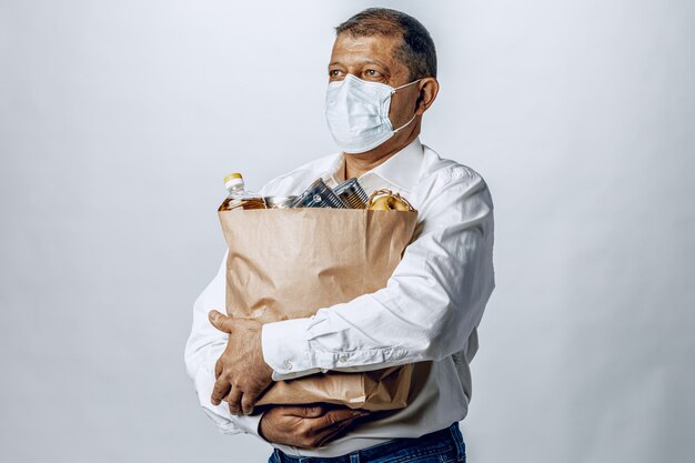 Hombre en una máscara médica protectora con una bolsa de una tienda de comestibles