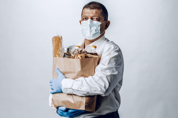 Hombre en una máscara médica protectora con una bolsa de una tienda de comestibles