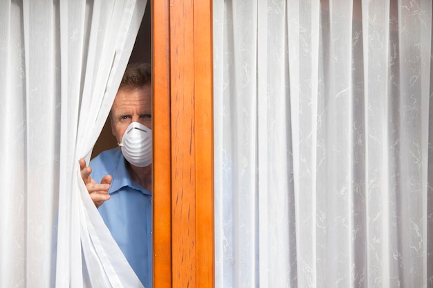 Foto hombre con máscara mirando por la ventana