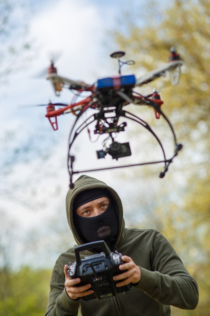 Hombre en máscara operando un dron con control remoto. Concepto de crimen