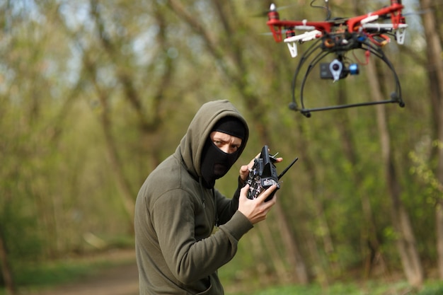 Hombre en máscara operando un dron con control remoto