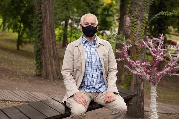 Hombre con máscara en el parque en un banco. Protección contra la enfermedad. Concepto de seguridad sanitaria